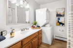Modern bathroom featuring a washer, hardwood cabinetry, and stylish decor in Independence Green Apartments.