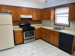 Spacious 2-bedroom apartment kitchen with modern appliances and hardwood cabinets, suitable for small dogs.