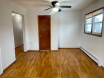 Bright living room of a large 2-bedroom apartment with hardwood floors and ceiling fan.