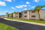 Exterior view of The Lodge at Woodlake Apartments in Lakeland, featuring spacious grounds and palm trees.