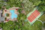 Aerial view of the community pool and tennis court at Park at Via Veneto in Jacksonville, FL, surrounded by lush trees.
