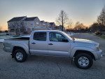 2010 Toyota Tacoma SR5 TRD Sport Quad Cab 4x4 in silver, clean condition, parked in residential area during sunset.