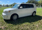 2008 Scion xB in white, low mileage, parked in a grassy area, showcasing efficient hatchback design.