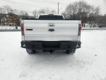 Rear view of a lifted 2014 Ford F-150 FX4 parked in snow, showcasing its sleek design and new wheels.