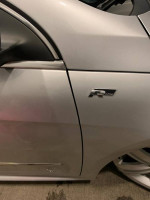 Close-up of 2010 Volkswagen CC R-Line badge on silver car door, showcasing sporty design features.