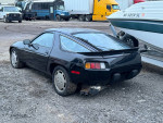 1985 Porsche 928 S V8 project car with modifications, currently non-running, parked beside trucks and boats.