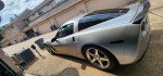2006 Chevrolet Corvette C6 Z51 in silver parked with a clear sky and garages in the background.