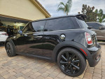 Side view of a 2013 Mini Cooper S Turbo parked on a driveway, showcasing sleek black design and alloy wheels.