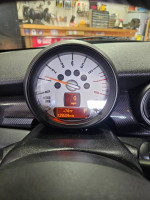 Dashboard of a 2013 Mini Cooper S showing 129,604 miles and temperature, parked in a workshop.