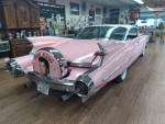 Classic pink Cadillac with Elvis theme displayed in a vintage car showroom