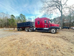 2002 Freightliner Century Class truck with dump trailer parked in a gravel area surrounded by trees