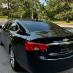 Black Chevrolet Impala showcasing sleek design, V6 badge, and tinted windows parked outdoors.