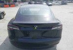 Rear view of a black 2020 Tesla Model 3 Standard Range Plus sedan with 49,256 miles, showcasing sleek design.