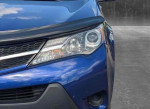 Close-up of a blue 2014 Toyota RAV4 LE front, showcasing its headlights and grille in good condition.