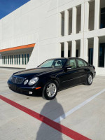2004 Mercedes-Benz E320 with 69,727 miles parked beside modern architecture, showcasing excellent condition and new tires.