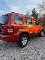 2009 Jeep Liberty in burnt orange color, parked on gravel, featuring excellent exterior and spacious interior.