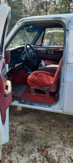Interior view of a 1990 Chevrolet Blazer with red seats and dashboard, showing steering wheel and controls.