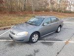 2009 Chevrolet Impala LS in excellent condition with 70k miles, parked on a clean lot surrounded by trees.
