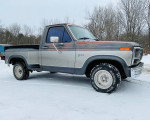 1985 Ford F150 stepside truck in silver, parked on snow-covered ground, showcasing classic design and features.