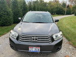 Front view of a 2010 Toyota Highlander SE FWD with minor scratches, parked in a grassy area