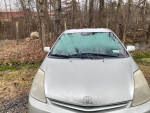Front view of a 2005 Toyota Prius hatchback parked in a wooded area with a dirty windshield.
