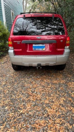 Rear view of a 2007 Ford Escape XLT SUV with red exterior parked on a gravel driveway.
