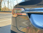 Close-up of a 2023 Tesla Model X tail light and badge, showcasing sleek design and mint condition.