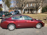 2012 Nissan Altima sedan parked on the street, showcasing its maroon exterior and modern design.