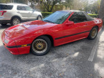 1988 Mazda RX7 convertible in excellent condition, featuring a red exterior and gold wheels, parked outdoors.