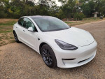 2021 Tesla Model 3 Standard Range Plus in white, parked outdoors with a gravel background