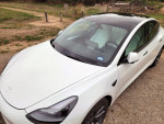 Top view of a white 2021 Tesla Model 3 with black roof, showcasing sleek design and stylish interior.