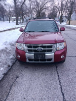 Red Ford Escape 4x4 parked on a snow-covered street, showcasing its front view.