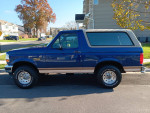 1996 Ford Bronco Eddie Bauer in midnight blue, 4WD, with low mileage parked on a sunny street.