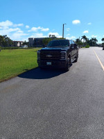 2023 Ford F-350 Super Duty XLT 4X4 crew cab in black, driven only 900 miles, parked on a sunny day.