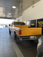 1990 Ford F250 IDI Diesel truck parked in a service area, showcasing its original yellow color and solid condition.