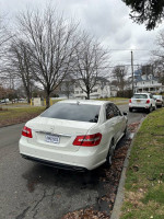 2010 Mercedes-Benz E-Class E550 sedan parked on a street with trees and houses in the background.