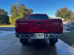 Rear view of a red 2003 Toyota Tacoma Pre-Runner with a tow package and upgraded exhaust in good condition.