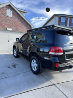 2008 Toyota Land Cruiser parked in front of a house with a roof rack, showcasing its sleek design.