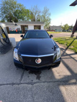 Front view of a black 2011 Cadillac CTS parked at a gas station, showcasing its sleek design and front grille.