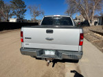 Rear view of a 2004 Ford F150 XLT truck parked on a dirt road, showcasing the tailgate and back tires.
