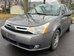 2011 Ford Focus SE Sedan in gray color, clean with 116,000 miles, parked on a wet asphalt road.