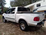 White Ford F-150 truck with a flatbed, parked outdoors, in good condition, available for sale.