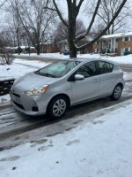 2014 Toyota Prius C in silver parked on snowy street, showcasing its well-maintained condition and clean title.