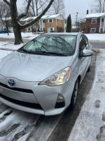 2014 Toyota Prius C in silver parked on snowy street, well-maintained with 103,000 miles, great fuel efficiency.