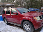 2007 Nissan Pathfinder in maroon with tan interior, parked in snowy setting, showcasing its 4x4 capabilities.