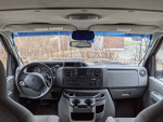Interior view of 2010 Ford E-350 cargo van with dashboard and steering wheel, showing spacious layout.