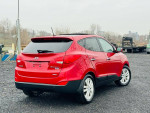 2013 Hyundai Tucson Limited AWD in red, showcasing a clean exterior and alloy wheels, ideal for highway driving.
