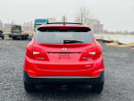 Red 2013 Hyundai Tucson Limited AWD parked by the water with cityscape in the background.