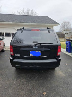 2007 Jeep Grand Cherokee with 126,000 miles parked in driveway, featuring a black exterior.