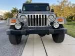 Front view of a 2005 Jeep Wrangler Rubicon Unlimited parked on the street, showcasing its distinctive grille and headlights.